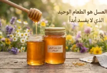 برطمان عسل طبيعي ذهبي مع ملعقة خشبية وأزهار برية – العسل هو الطعام الوحيد الذي لا يفسد أبداً